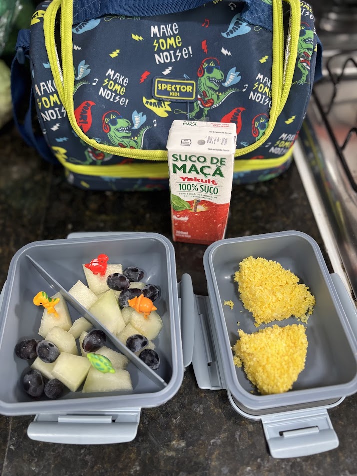 Lancheira contendo manga, panqueca de banana e agua de coco integral,